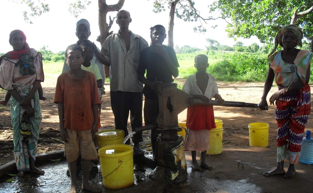 Dorfbewohner mit gelben Wasserkanistern am Brunnen in Mamba Village